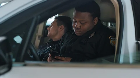 Handsome young men cops sitting use phone in patrol car accepting emergence call Stock Footage 112999529