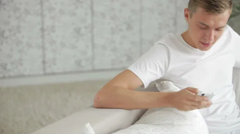 Handsome young men sitting on sofa and using cellphone with smile Видео 27692056