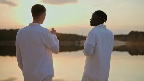 Handsome young men spend sunset at the beach, drinking and talking Stock Footage 197167189