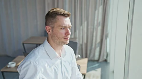 Handsome young mid-aged man standing near the window. Male takes off his glasses Stock Footage 217425981