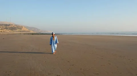 A handsome young moroccan man dressed as a berber walking on a sand beach Stock Footage 44782795