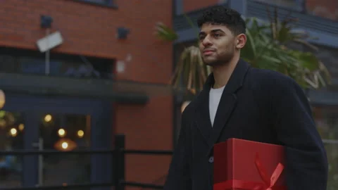 Handsome young multi ethnic man is walking on the street holding the new year Stock Footage 224344103