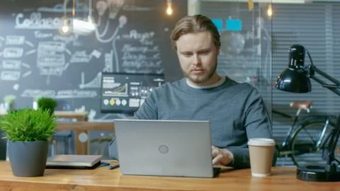 Handsome Young Office Employee Thinks on a Problem Solution While Typing on a Foto stock