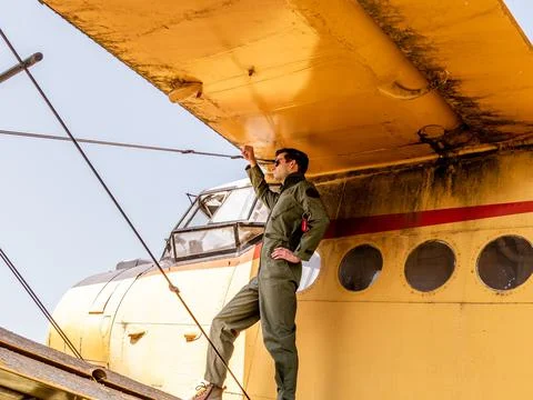 A handsome young pilot standing on the wing of a plane Stock Photos