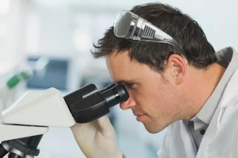 Handsome young scientist looking through a microscope Fotos Stock