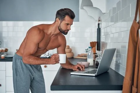 Handsome young shirtless man using laptop Фото