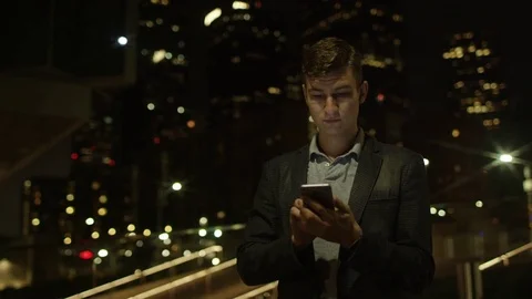 Handsome young student is using his smartphone for social networks while Stock Footage 77578113