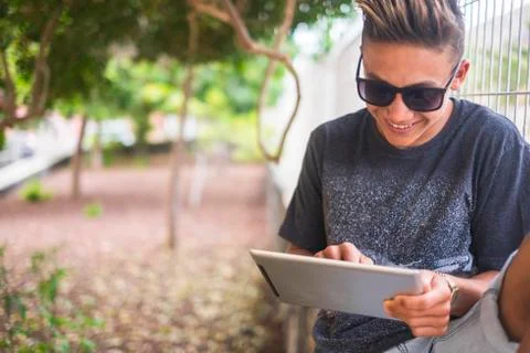 Handsome young teenager boy use laptop device oudoor with garden in backgroun Stock Photos