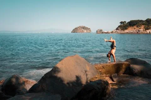Handstand on ocean front rocks Stock Photos