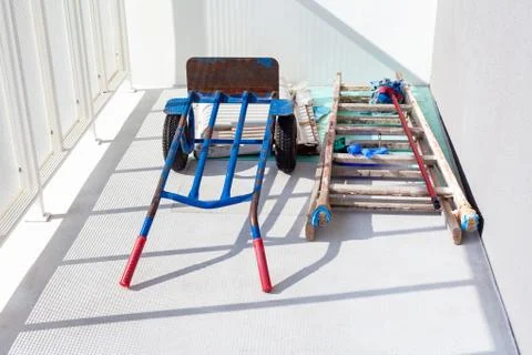 Handtruck and a wooden painter ladder and a mop laying on the white balcony Stock Photos