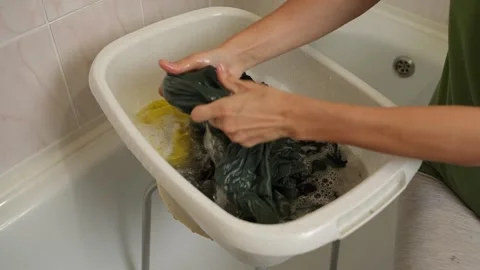 Handwashing laundry in a plastic basin. Close-up of a woman scrubbing clothes in Video stock 316755224