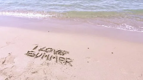 Handwritten message 'i love summer' on a pristine beach with gentle waves Stock Footage 283532205