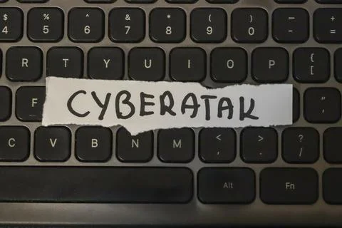 Handwritten note reading CYBERATAK on a computer keyboard symbolizes cyber Stock Photos
