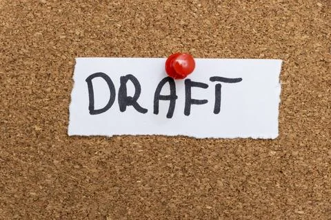 A handwritten note reading DRAFT pinned to a cork board, indicating an Stock Photos