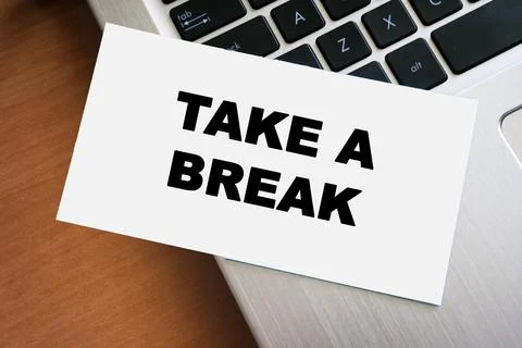 Handwritten note reading TAKE A BREAK on a white paper sheet rests on a laptop Stock Photos