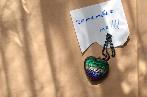 Handwritten note Remember Me in a white piece of paper. Wooden amulet in the  Stock Photos