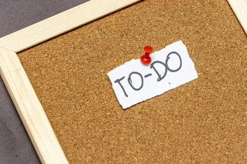 Handwritten note stating TO-DO pinned on a corkboard, symbolizing tasks and Stock Photos