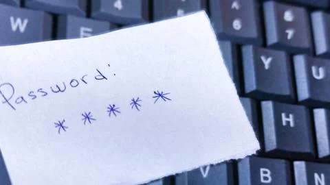 A handwritten password on a note resting on a keyboard serves as a stark il.. Stock Photos