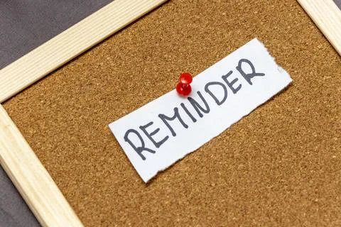 A handwritten reminder note pinned to a cork board, showcasing the importance of Stock Photos