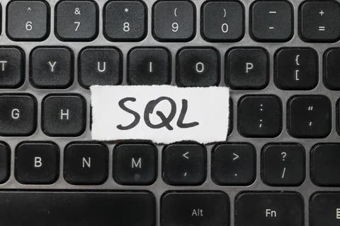 Handwritten SQL on a white paper strip placed on a modern black keyboard. This Foto stock