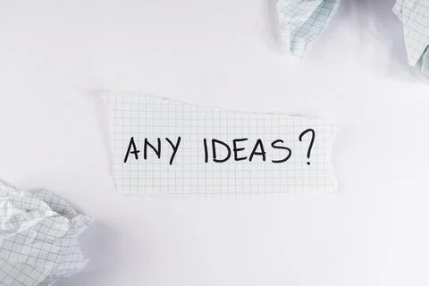 Handwritten text asking for any ideas on a small piece of torn grid paper s.. 스톡 사진