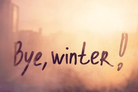 Handwritten text Bye winter on muddy glass wet orange window in city on sunse Stock Photos
