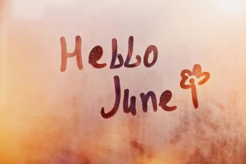 Handwritten text Hello June and flower shape on wet orange window Stock Photos