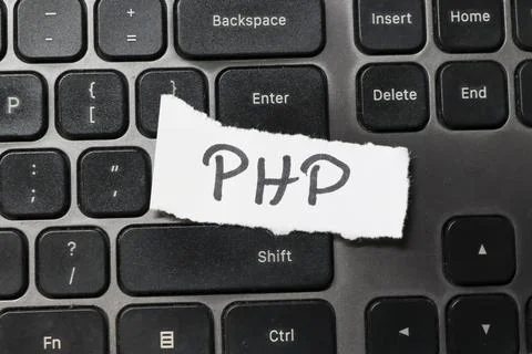 Handwritten text PHP displayed on a torn paper placed over a black keyboard, 写真素材