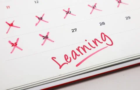 Handwritten word Learning in red ink on a paper calendar with several dates.. Stock Photos