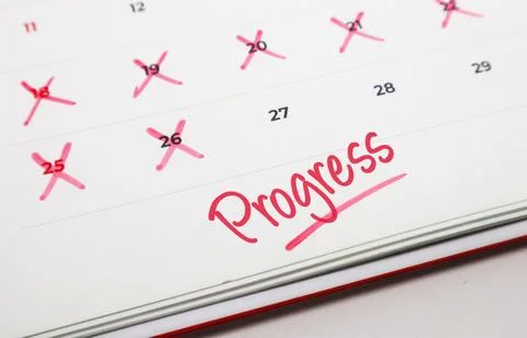 Handwritten word Progress in red ink on a paper calendar with several dates.. Stock Photos