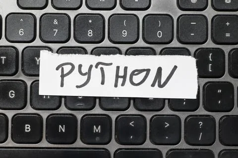 Handwritten word PYTHON on a piece of paper placed on a black keyboard, 写真素材