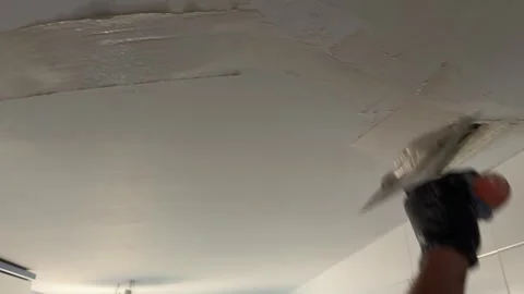 Handyman applying plaster to a damaged ceiling with a trowel Видео 341362882