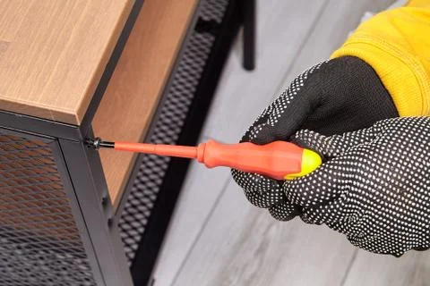Handyman is assembling flat pack TV stand using screwdriver. Stock Photos