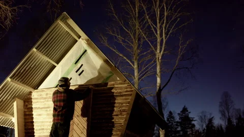 Handyman clads wooden cabin using planks preserved in shou sugi ban method Stock Footage 295206632