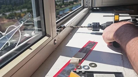 Handyman Drilling a Hole in PVC Window Frame for Lock Installation Stock Footage 340546979