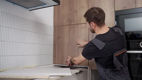Handyman fitting a cabinet door panel in a modern kitchen Stock Footage 329480747