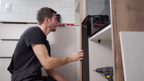 Handyman fitting kitchen cabinet panel during installation Stock Footage 329935624