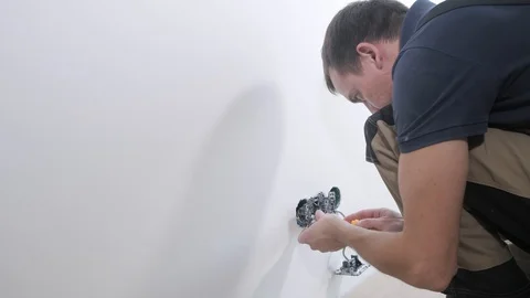 Handyman fixes light switch basis with screwdriver Stock Footage 106377018