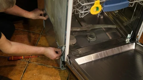 Handyman fixing broken dishwasher machine with a screwdriver. 库存影片 123604277