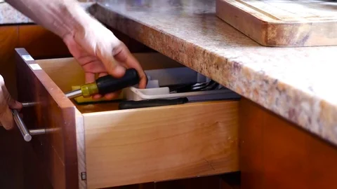 Handyman fixing drawer with screwdriver in kitchen Stock Footage 71837260