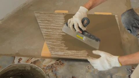 Handyman in gloves plasters ceramic tile with drywall knife Stock Footage 151810363