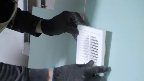 Handyman hands try on ventilation grill into drywall hole Stock Footage 108581872