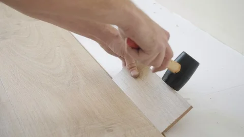 Handyman hits brown laminate using small wooden bar hammer Stock Footage 106376859