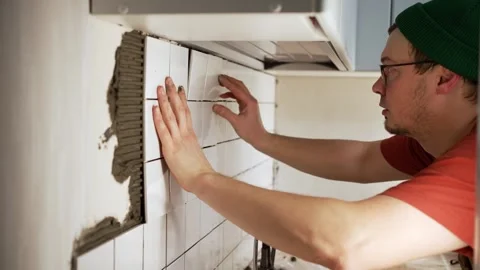 Handyman installing ceramic tile on a kitchen wall backsplash during a home Stock Footage 344565608