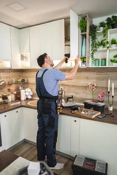 Handyman installing kitchen cabinets using electric screwdriver Stock Photos