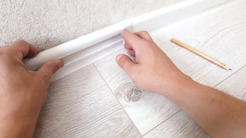 Handyman installing plastic baseboard molding in a room Video stock 326150446