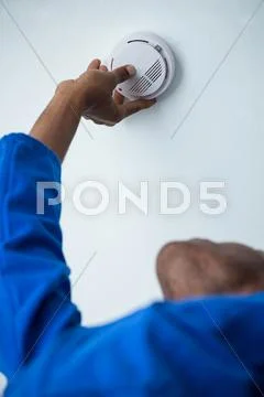 Handyman installing smoke detector on the ceiling Stock Photos