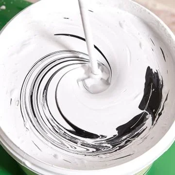 Handyman makes gray color while mixes black and white using drill. Stock Photos