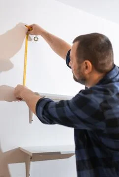 Handyman making marks on the wall for bookshelf mounting, person doing home.. Stock Photos