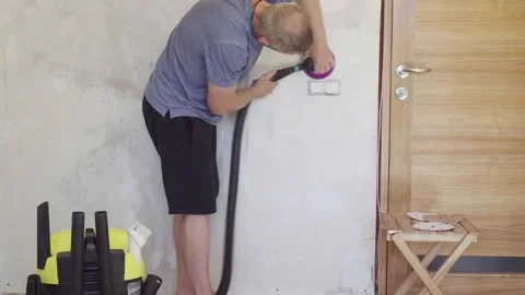 Handyman meticulously preparing textured wall surface with orbit sander Stock Footage 330417210